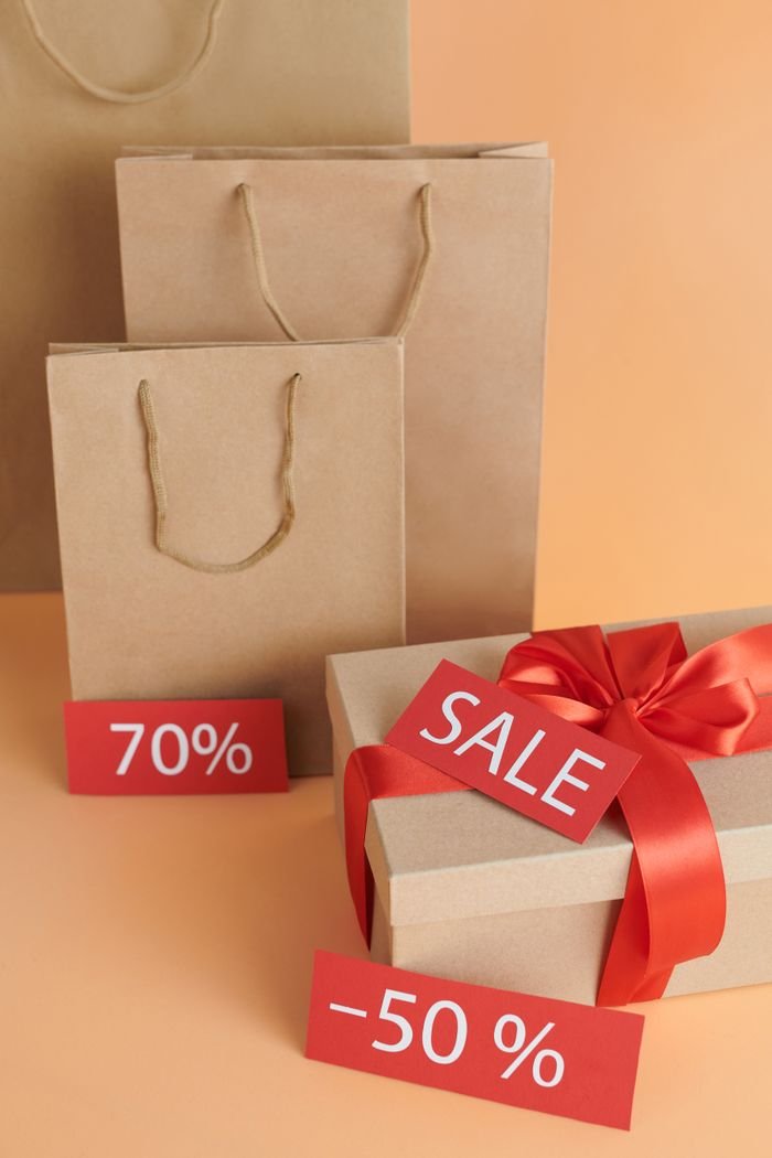 Elegant cardboard gift and shopping bags showcasing sale offers.