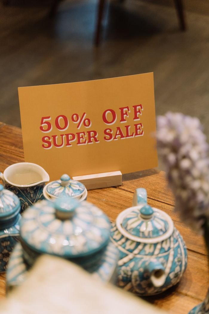 Elegant blue teapot set on wooden table with 50% off sale sign displayed.
